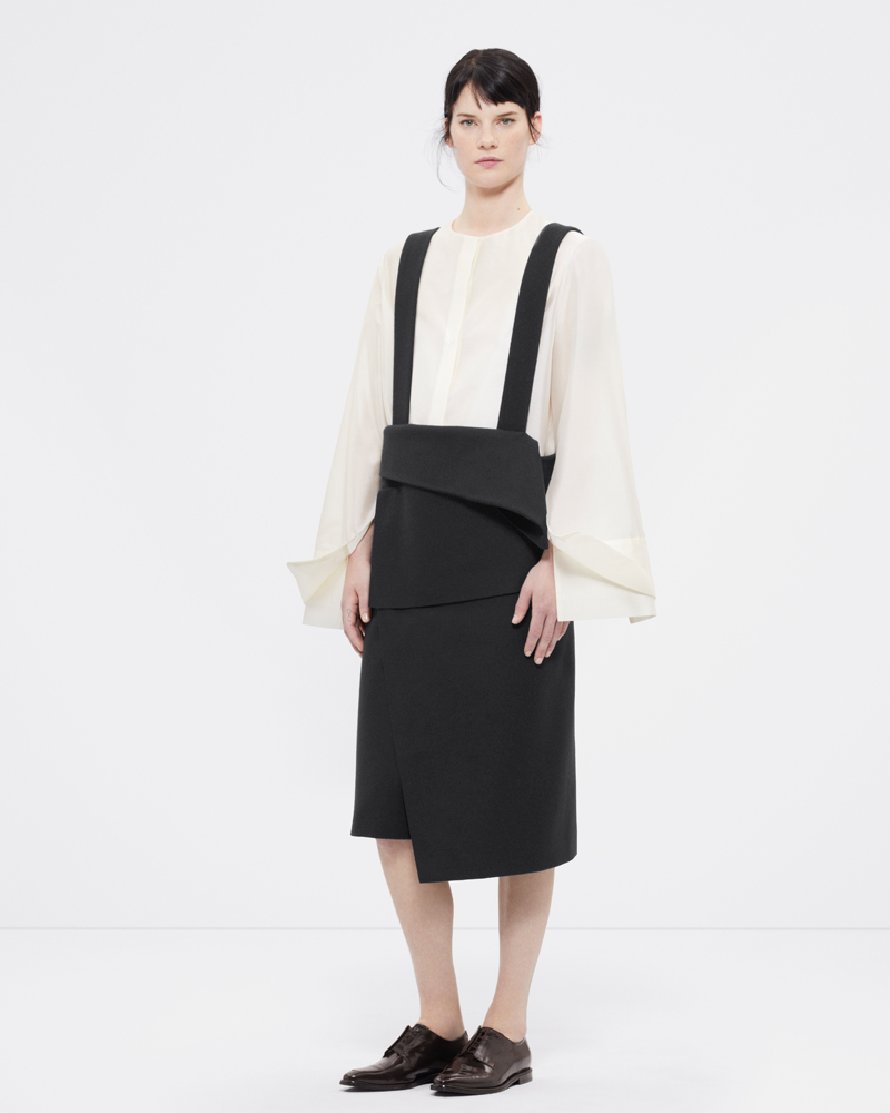 Re-proportioned collarless shirt with layered cuffs in off-white and a wool wrap skirt with suspenders in black 