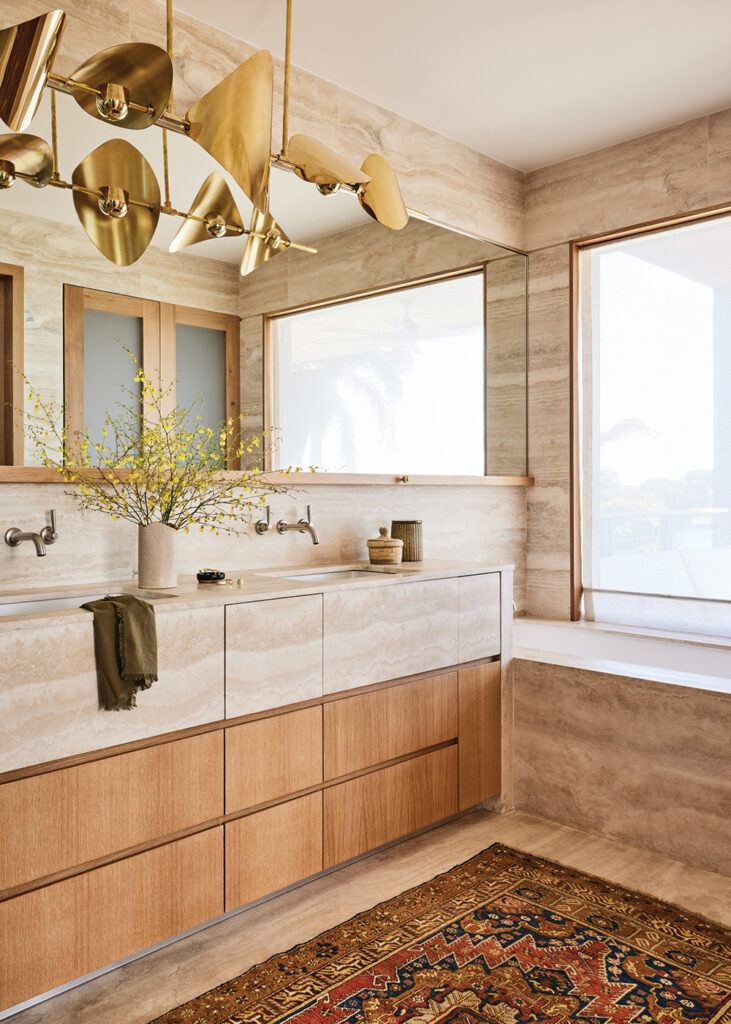 Tropical influences the primary bathroom that features wooden and metallic elements oil in this Miami home.