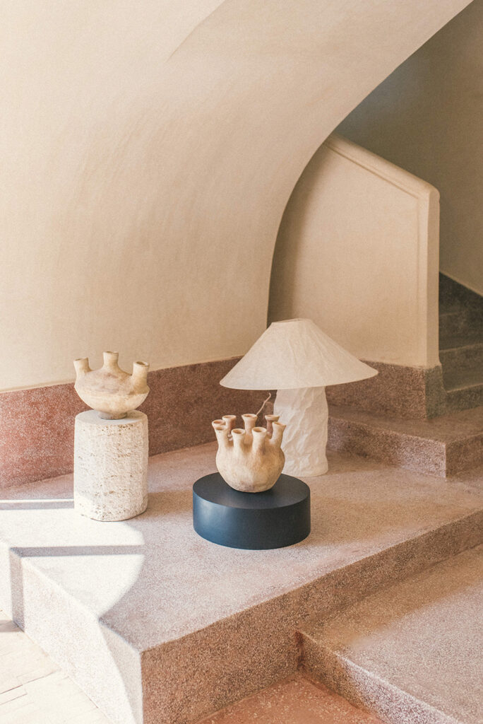 The mini totems are from La Marrakechoise and the painted round wooden base is from Barcelona-based Another Again; they are set alongside locally sourced pottery and Ingo Maurer’s Lampampe paper lamp