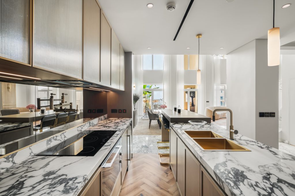 A luxurious kitchen complemented by viola marble, warm oak and bronze accents. This penthouse kitchen is functional space, perfect for culinary exploration