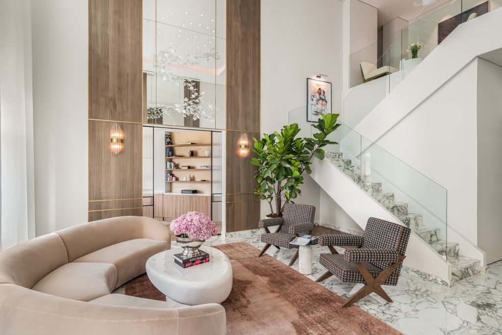 The neutral tones of the pink wrap around couch and Persian rug complement the striking staircase, adding to the penthouse's allure 