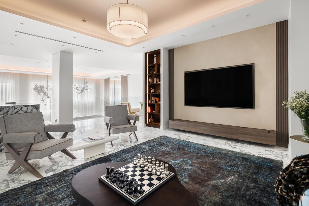 The upstairs living room holds all forms of entertainment with a mounted TV, Missoni-inspired tweed chairs and a wrap-around couch.