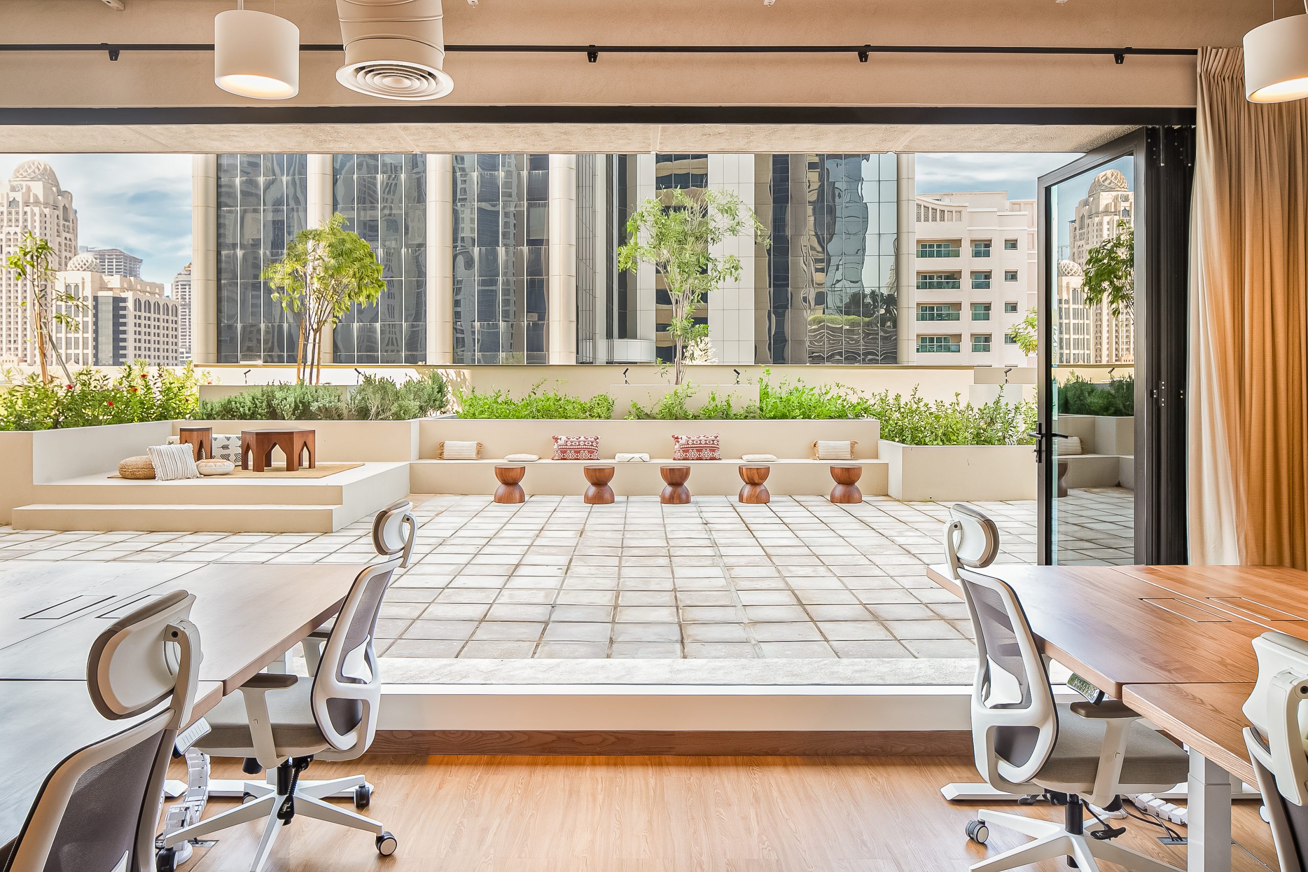 the outdoor majilis, decorated with wooden stools, poufs and colorful pillows in the Beyond One's office