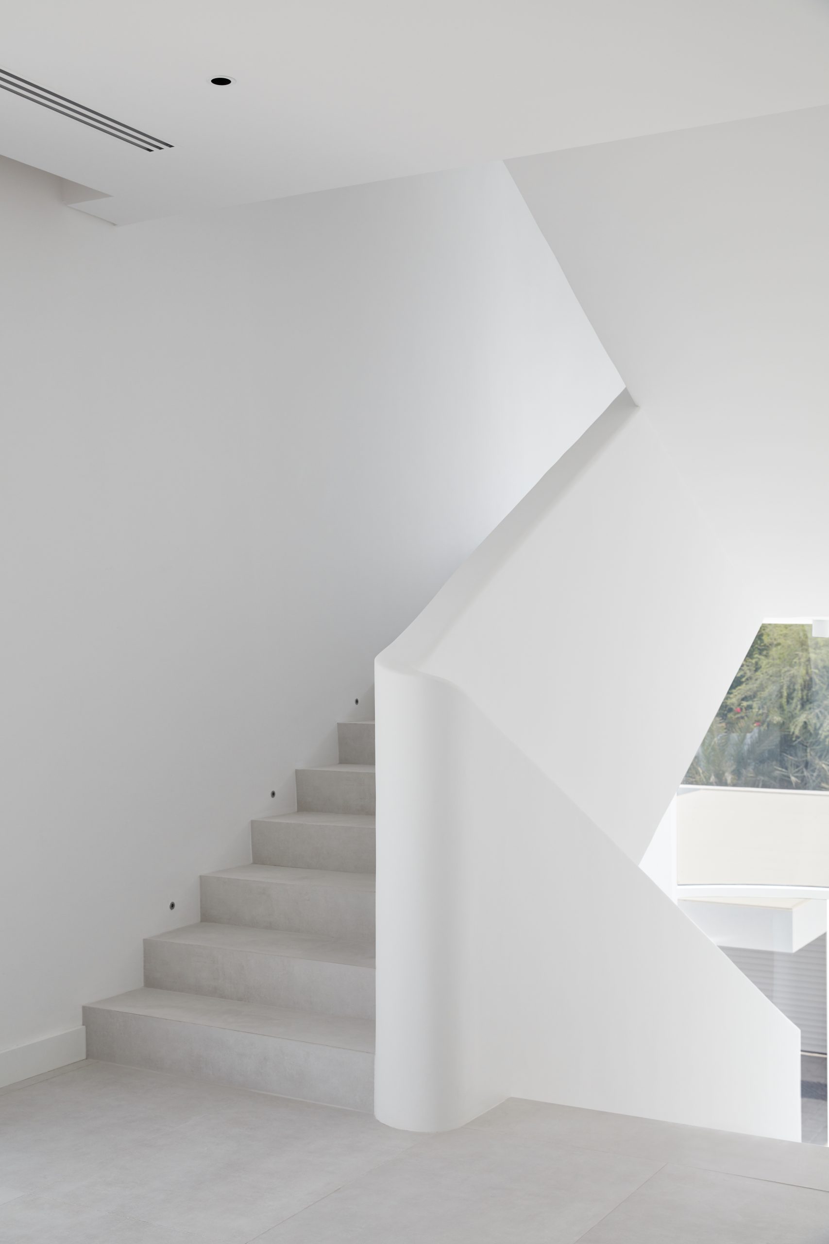 White staircase with white railing that are designed to look as if they are flowing up & down the staircase