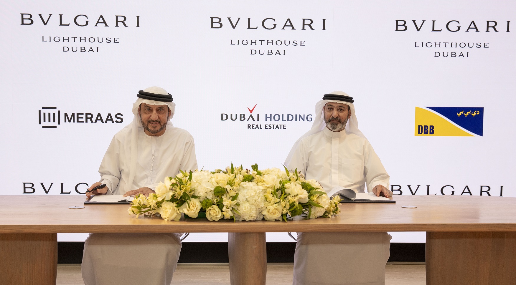 a table with two men signing the contract for The Bvlgari Lighthouse