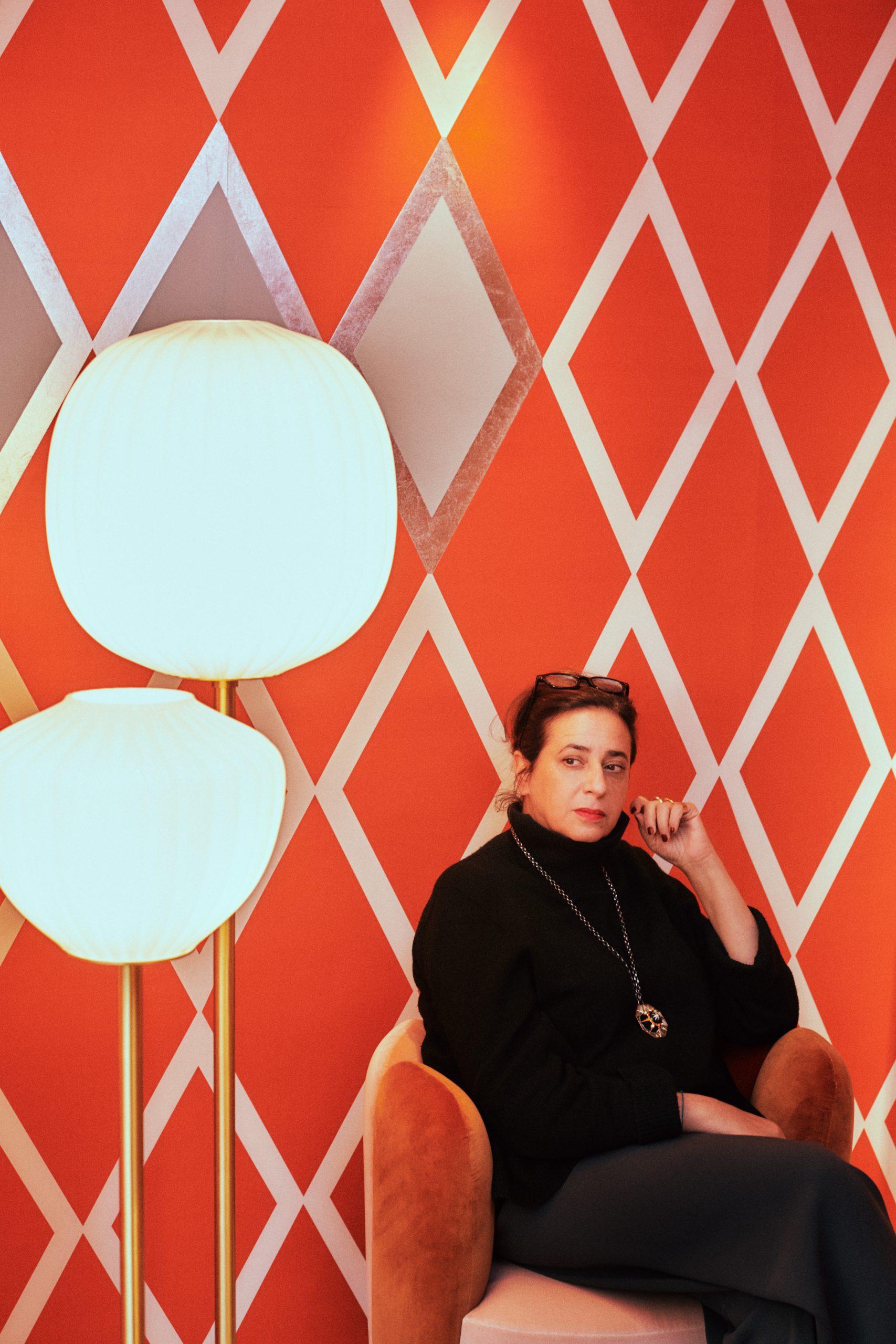 A picture of a woman, India Mahdavi, sitting on a chair in her studio