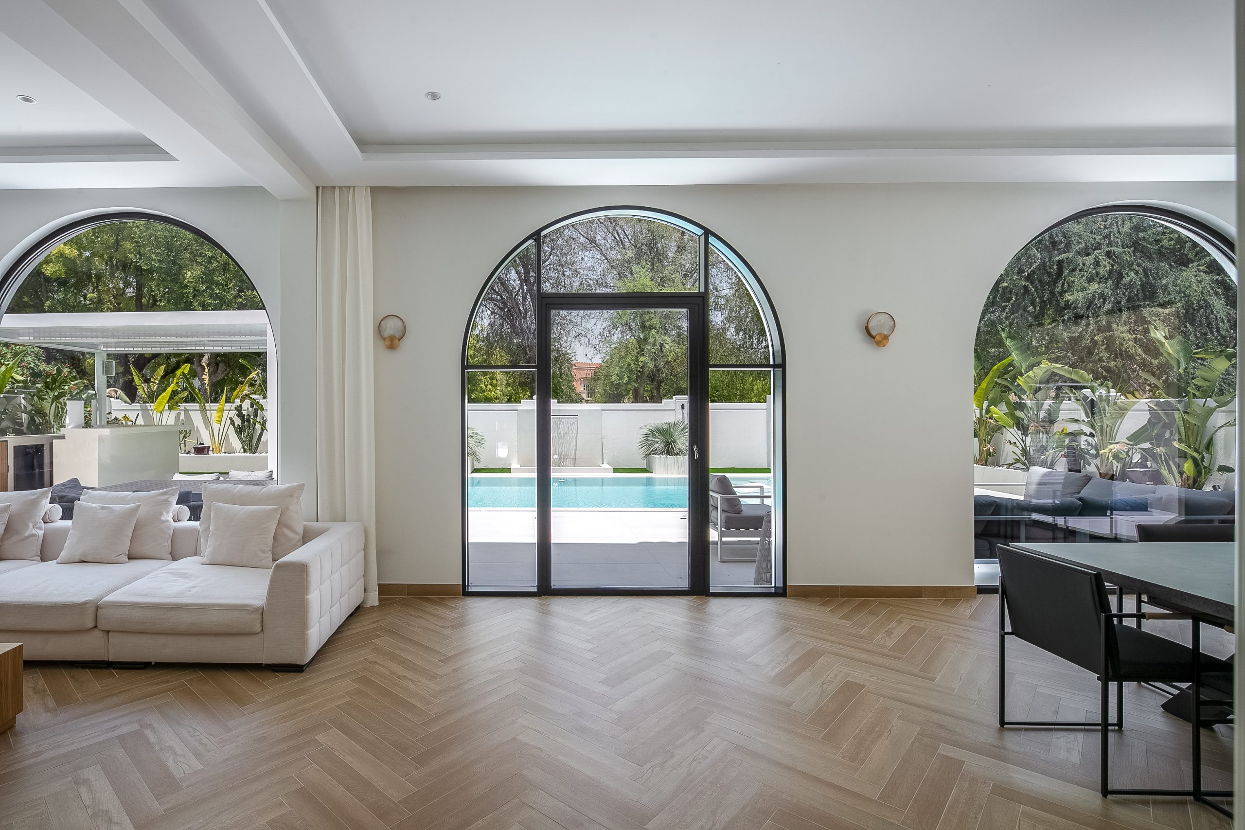 A room with arched windows and a pool in the background