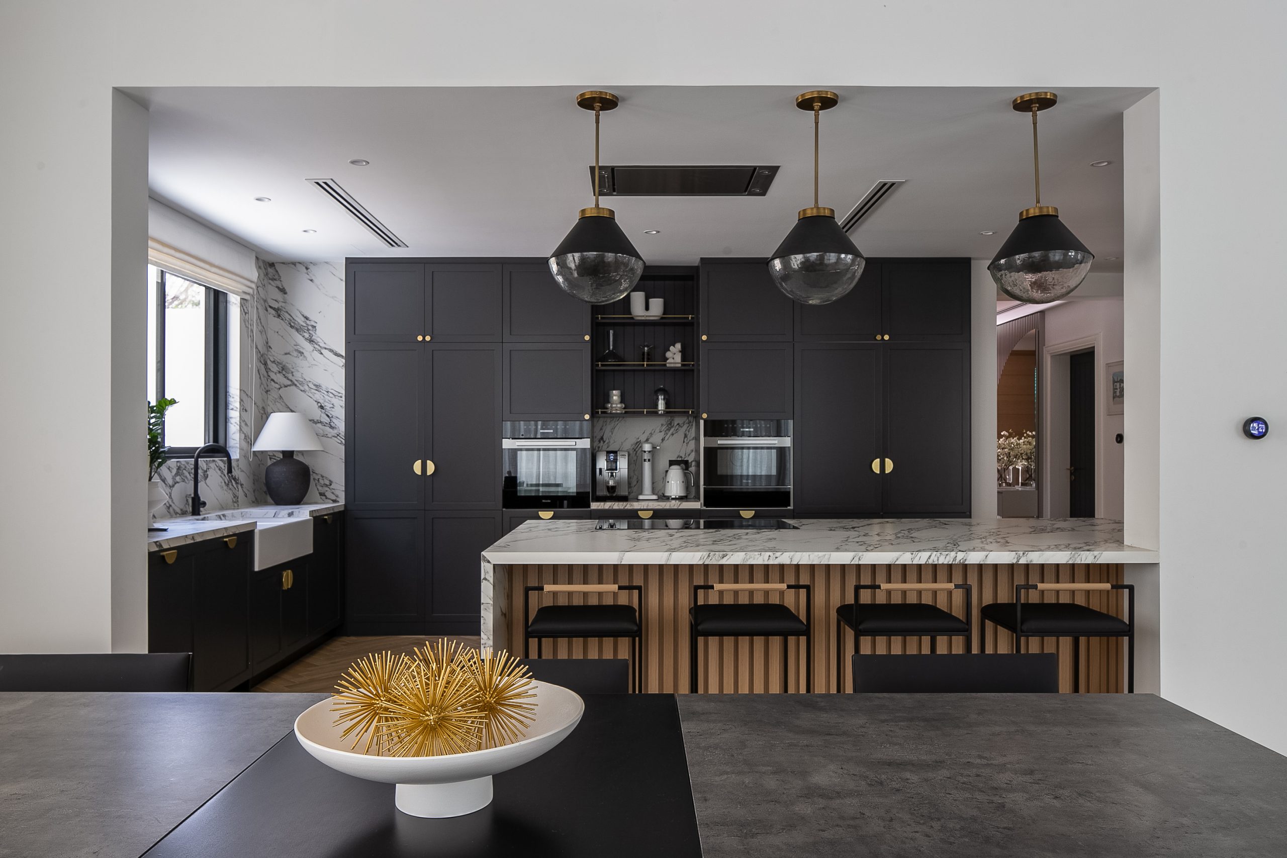 open-concept layout in the kitchen that has dark cabinetry with gold accents and an island