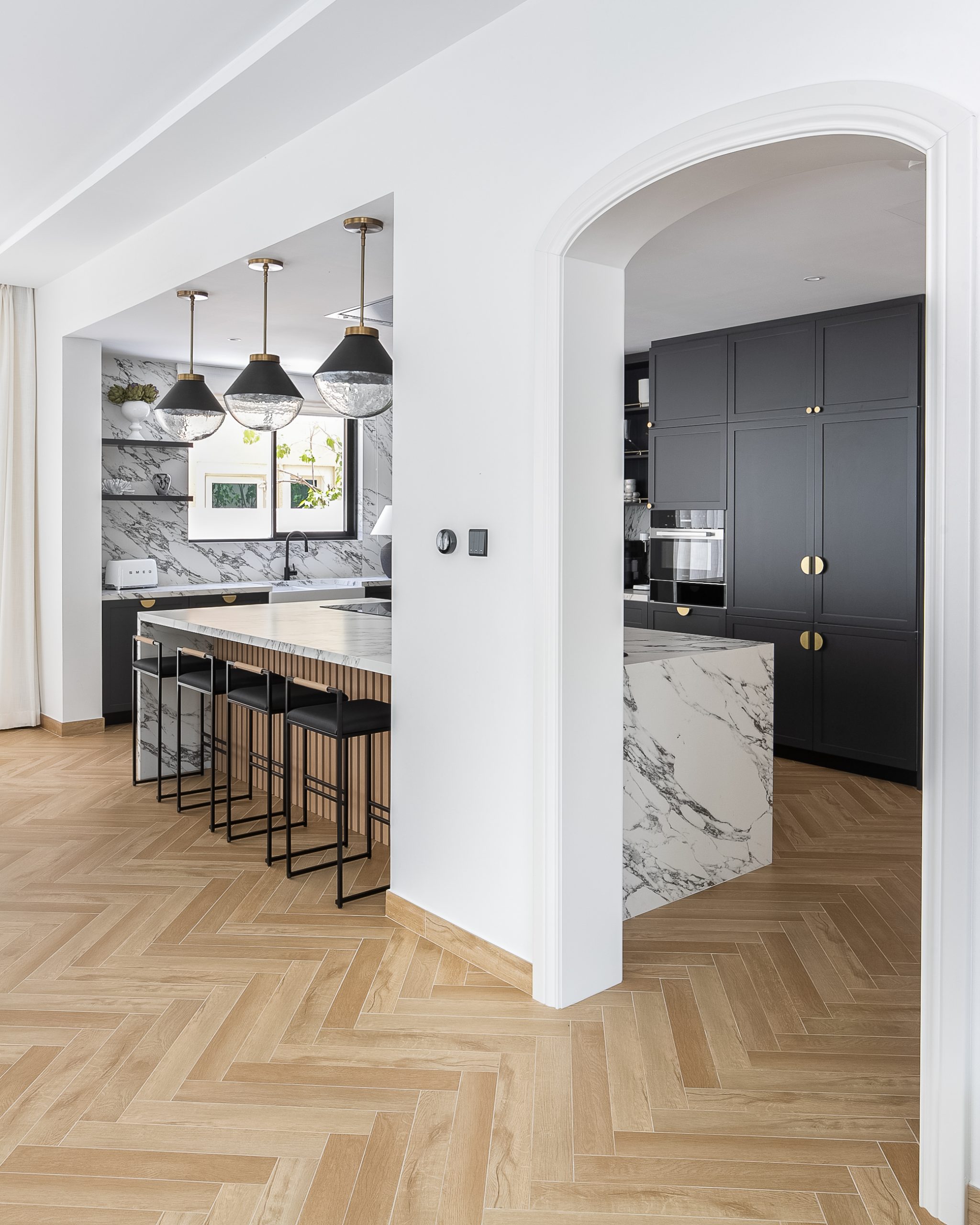 open-concept layout in the kitchen that has dark cabinetry with gold accents and an island