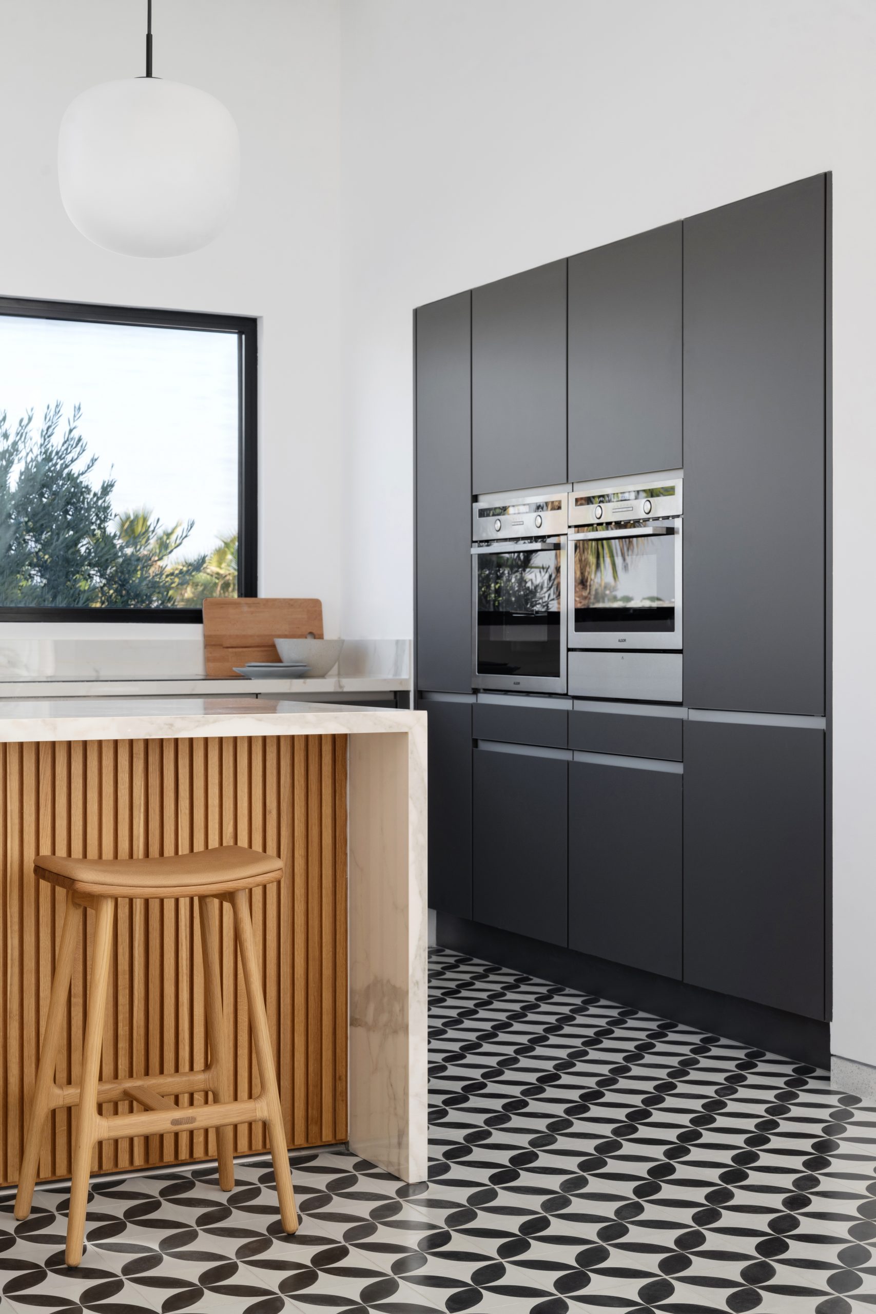 a kitchen with black cabinets with embedded oven and microwave