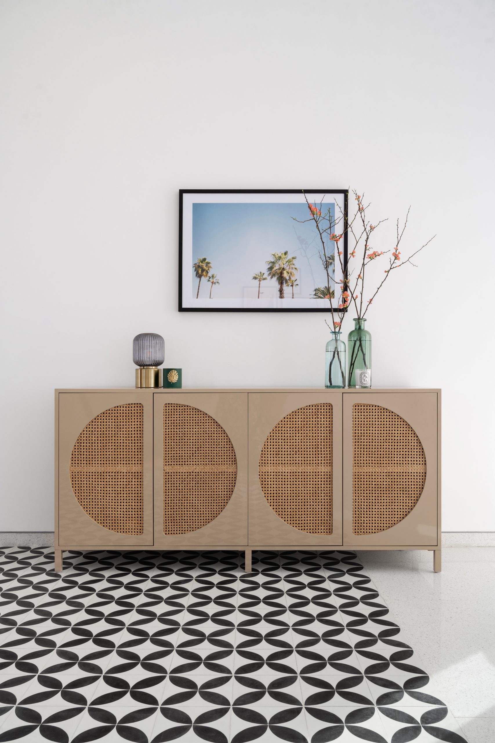 a chest with 4 semicircles that are designed with textured material placed and each semicircle parallel to another. Decorations include a vase, painting and a rug with black geometric pattern