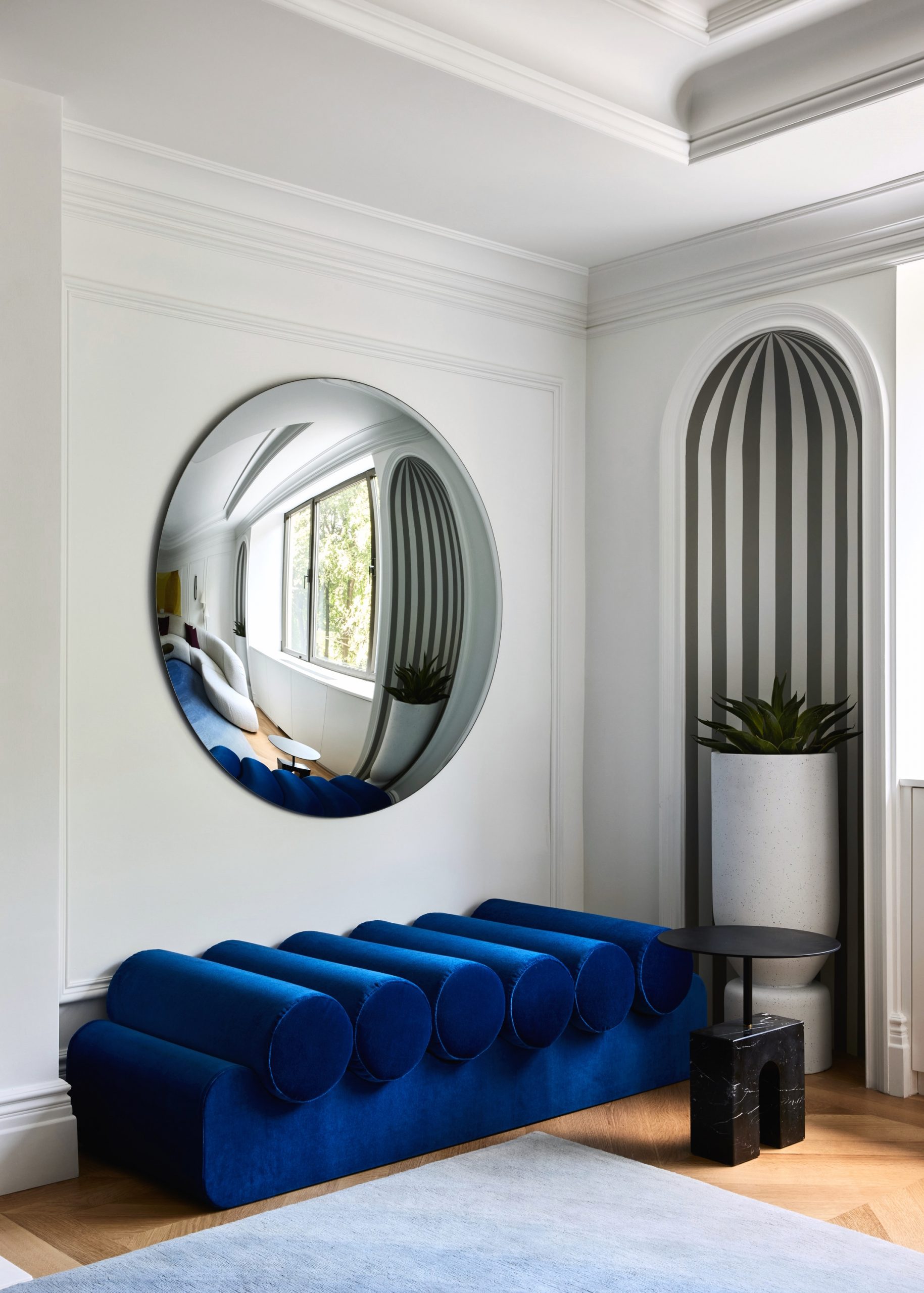 A mirror on the wall with a blue seat under at 955 fifth avenue 