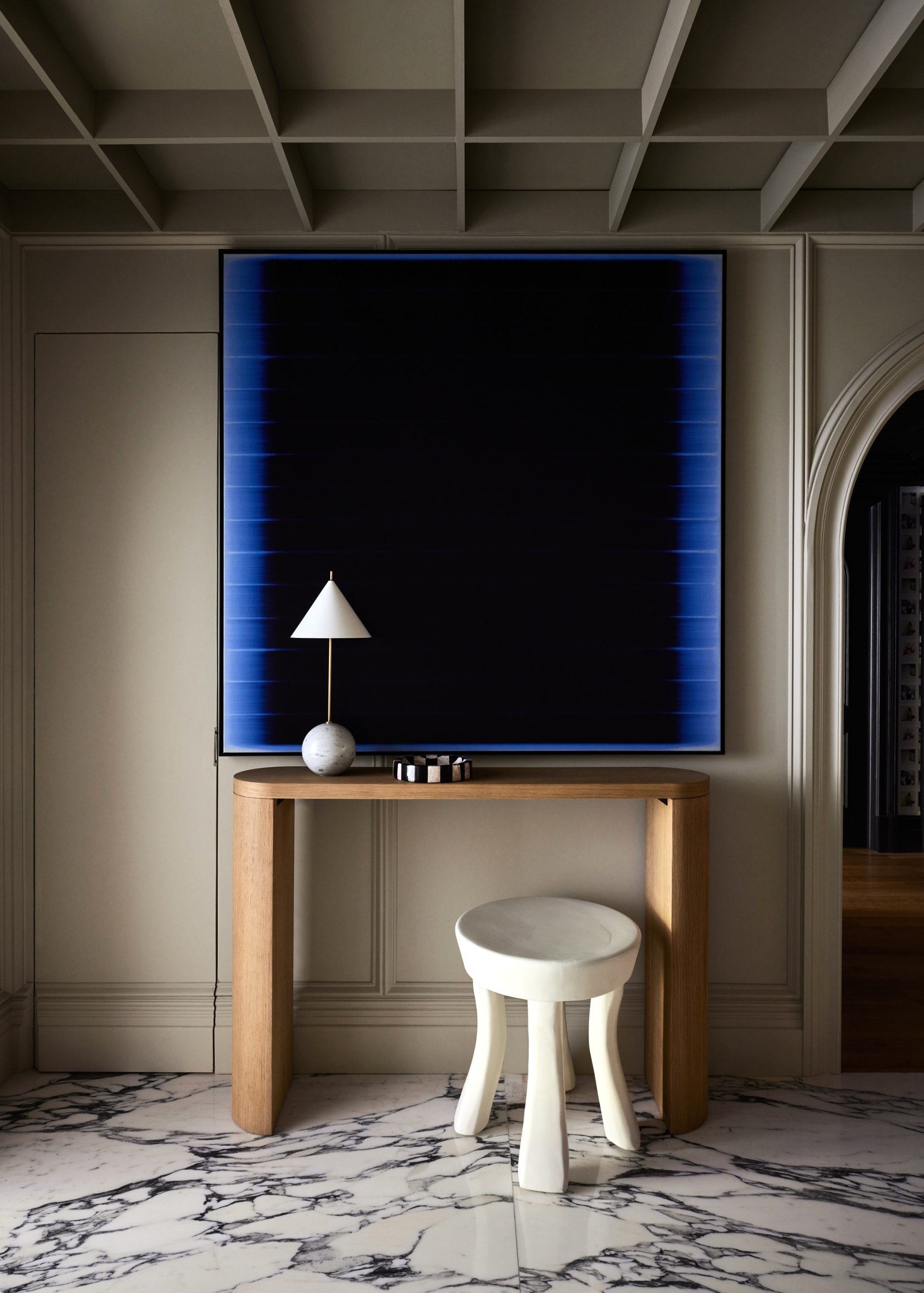 A table and stool in a room with an abstract painting